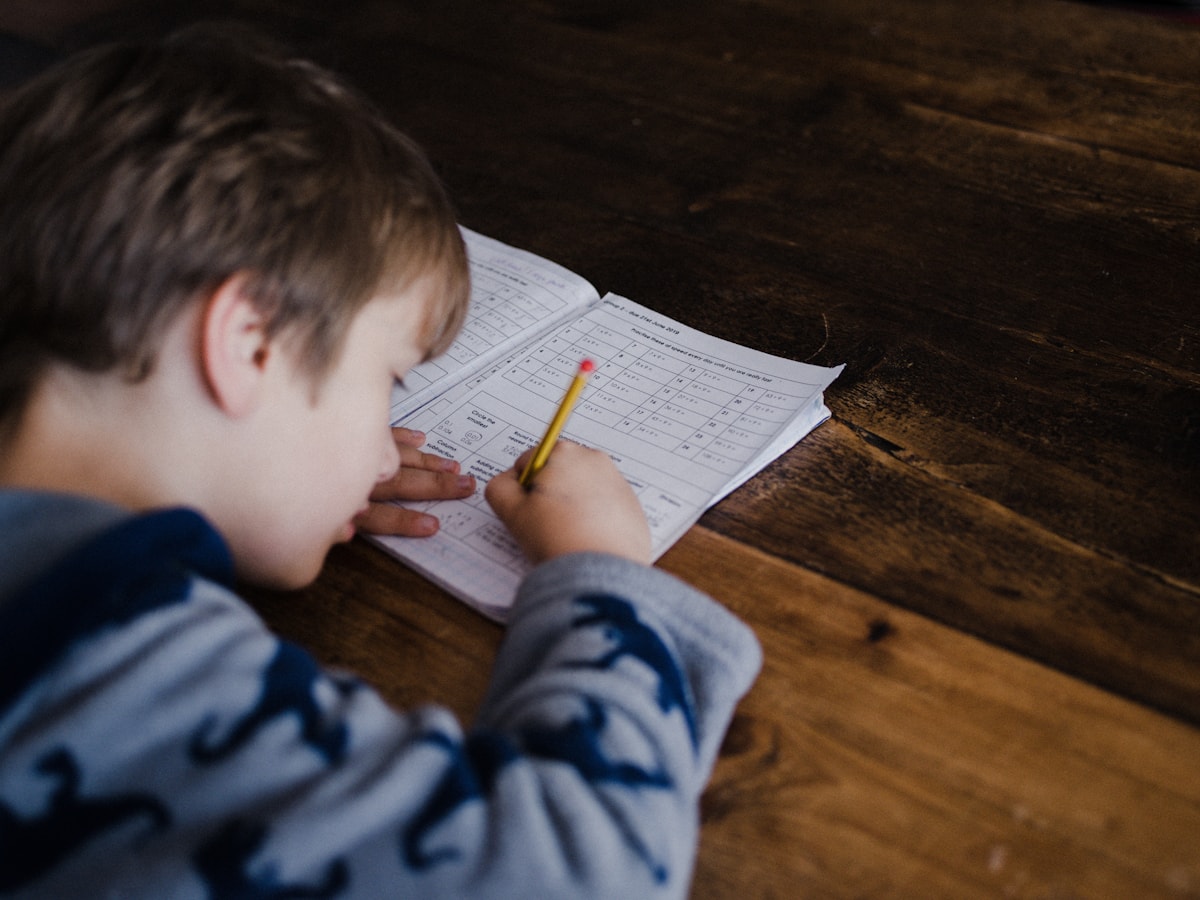 Student writing out a maths problem at a table